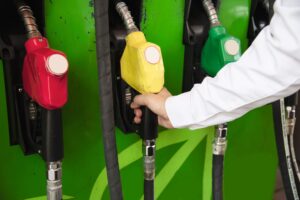 Ilustrasi truk pengangkut biodiesel B50 dengan latar fasilitas penyimpanan bahan bakar dan perkebunan kelapa sawit di Indonesia.